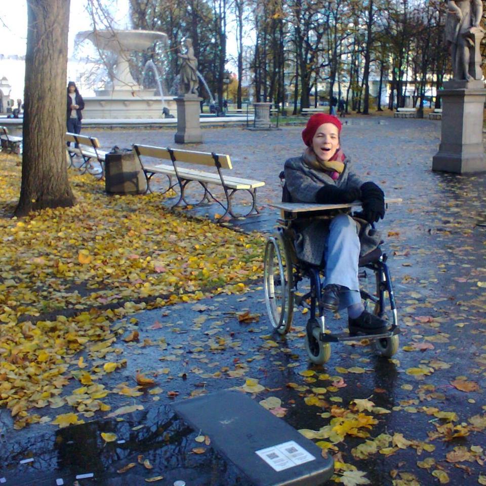 Agnieszka Bal (foto 2017) na starym wózku, z nieodłączną tablicą literową, dzięki której porozumiewa się z nami.
